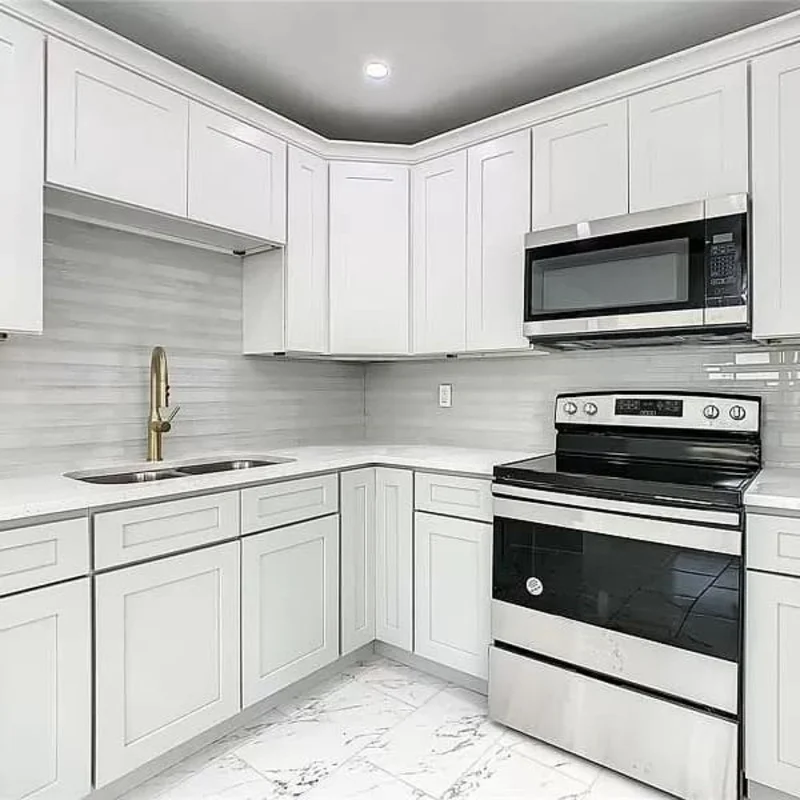Full-height quartz slab backsplash coordinating with white cabinets and under-cabinet lighting Full-height quartz slab backsplash coordinating with white cabinets and under-cabinet lighting