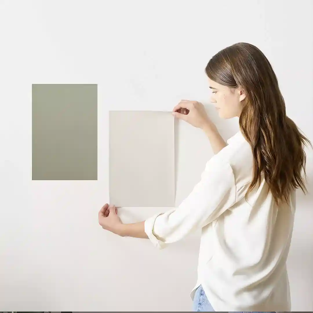 A professional color consultant comparing large paint swatches to a living room wall under natural light - professional color consultant A professional color consultant comparing large paint swatches to a living room wall under natural light - professional color consultant