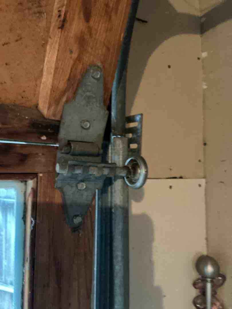 A homeowner visually inspecting the photo-eye sensors of their garage door, ensuring they are clean and aligned for proper safety function - garage door maintenance in lakeway tx