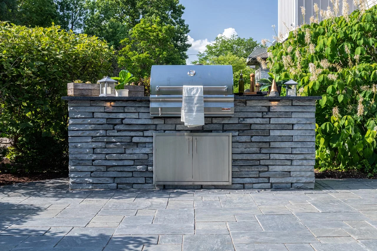 A custom outdoor kitchen built with brick veneer and granite countertops - backyard brick design