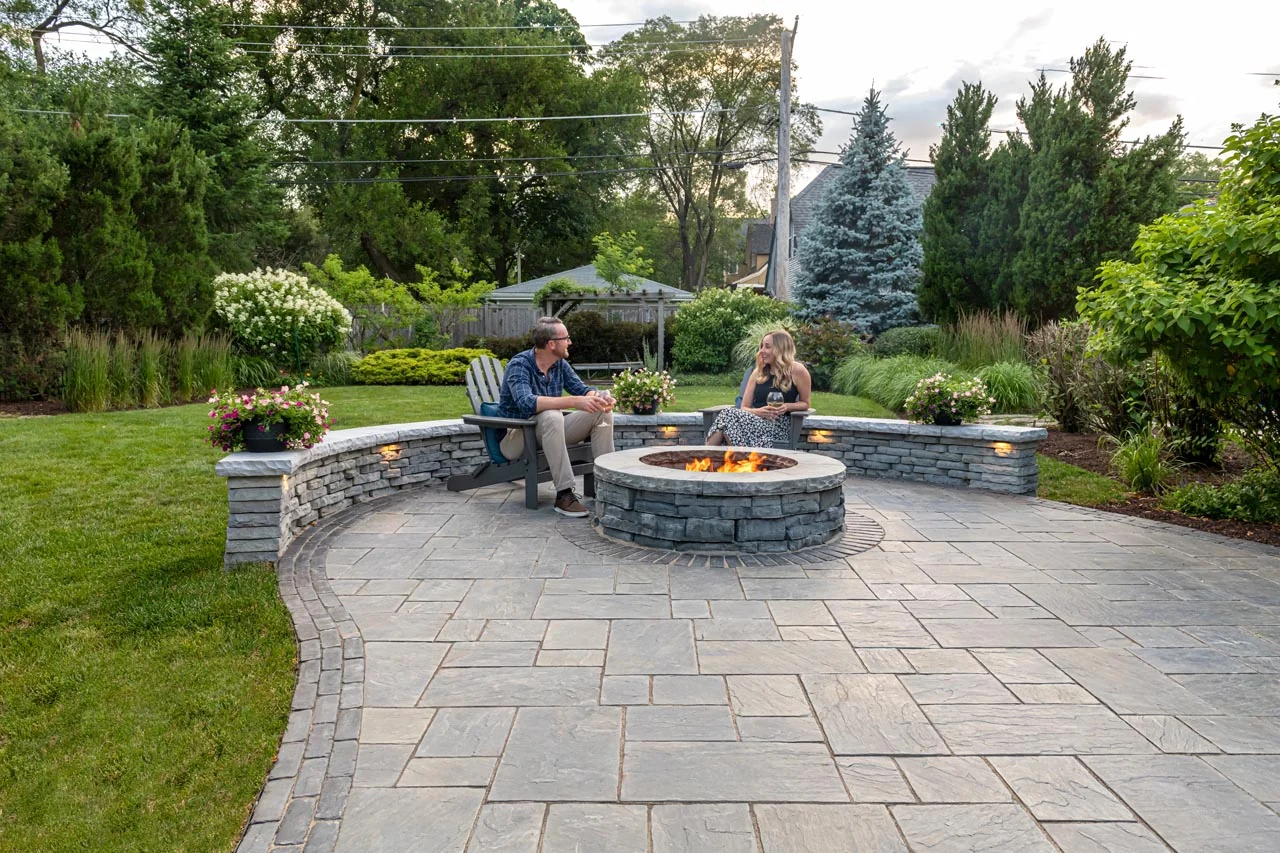 A beautifully completed custom brick patio featuring a built-in fire pit and clean, modern borders