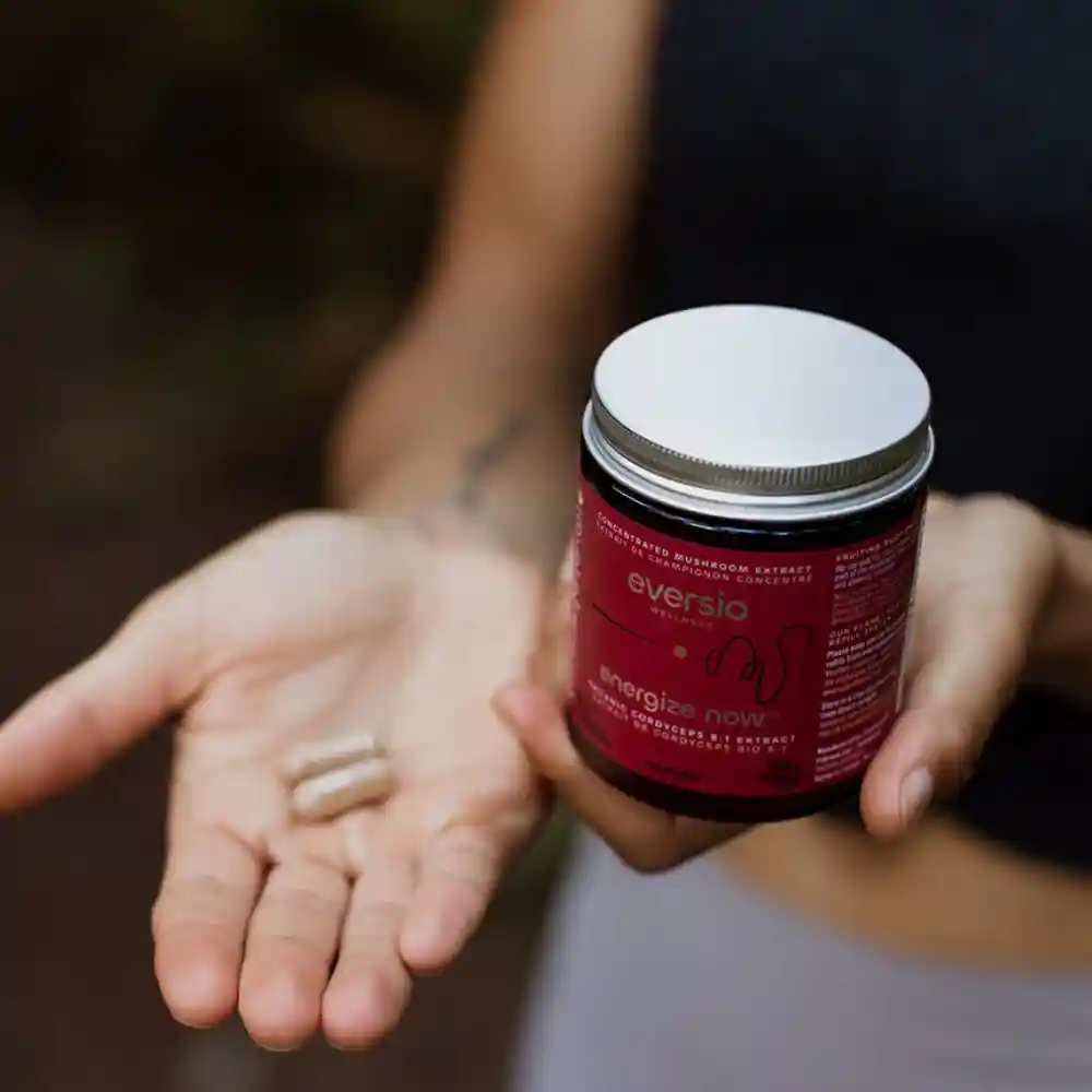 A woman's hands holding Eversio's "Energize Now" Cordyceps capsules and jar, representing powerful natural health solutions.