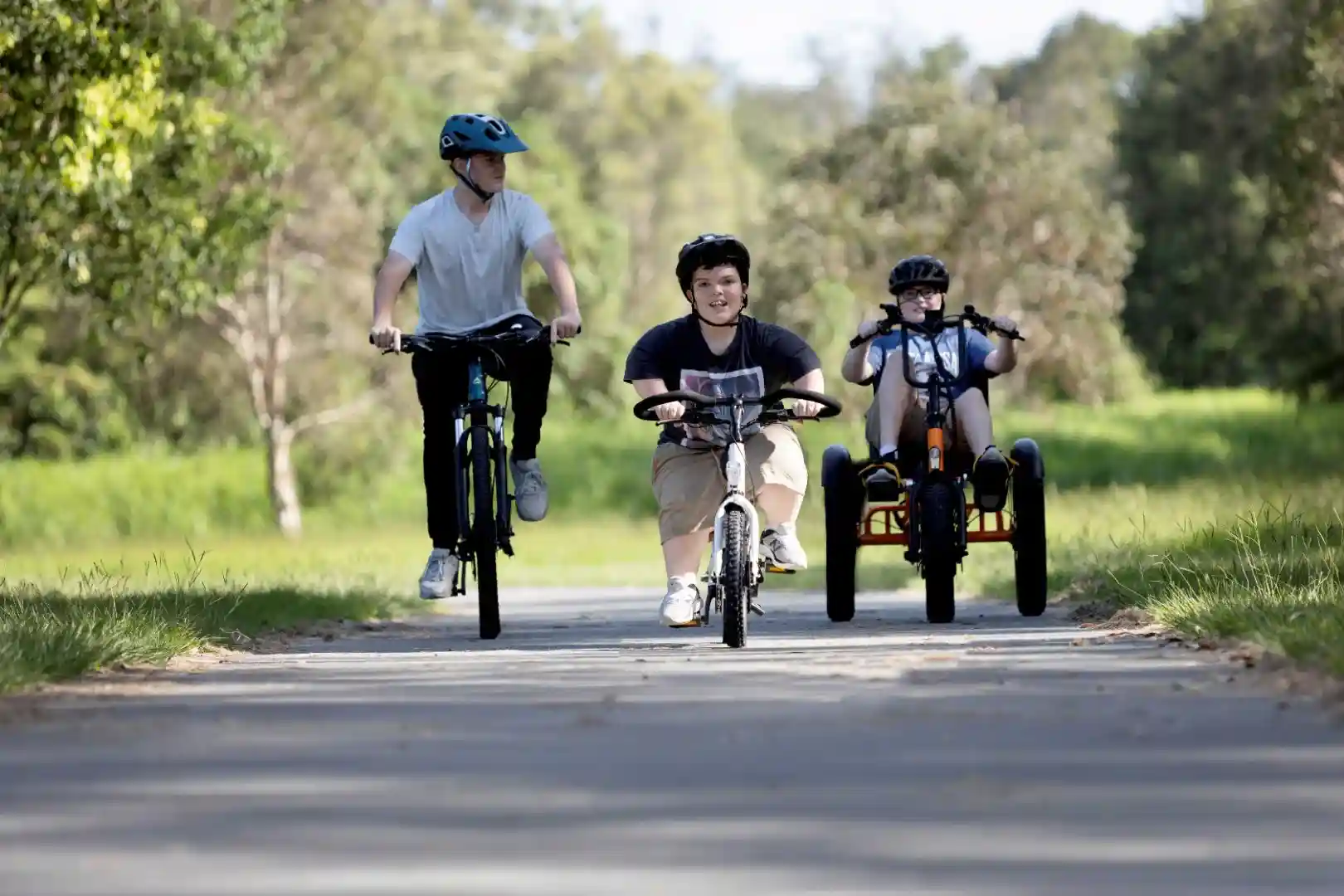 A diverse group of happy people riding electric trikes and bikes together on a sunny path - electric tricycle servicing
