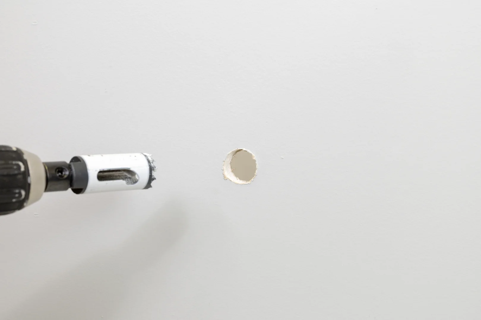 Hole saw drilling into drywall for anchor installation Hole saw drilling into drywall for anchor installation