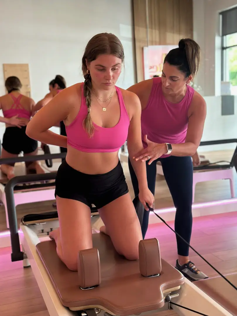 Instructor guiding a beginner on a Reformer machine, ensuring proper alignment and form - beginner friendly pilates classes