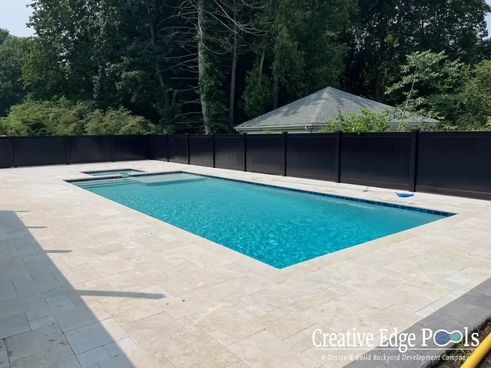 Custom gunite pool with integrated spa and travertine decking Custom gunite pool with integrated spa and travertine decking