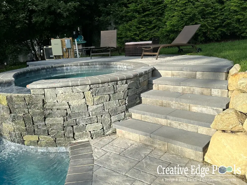 Custom spa and pool combo with integrated lighting and stone masonry - pool builders Weston