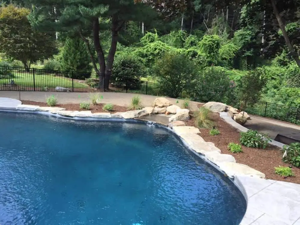 Inground pool landscaping around pool with rocks and perennial plantings - backyard pool design Inground pool landscaping around pool with rocks and perennial plantings - backyard pool design
