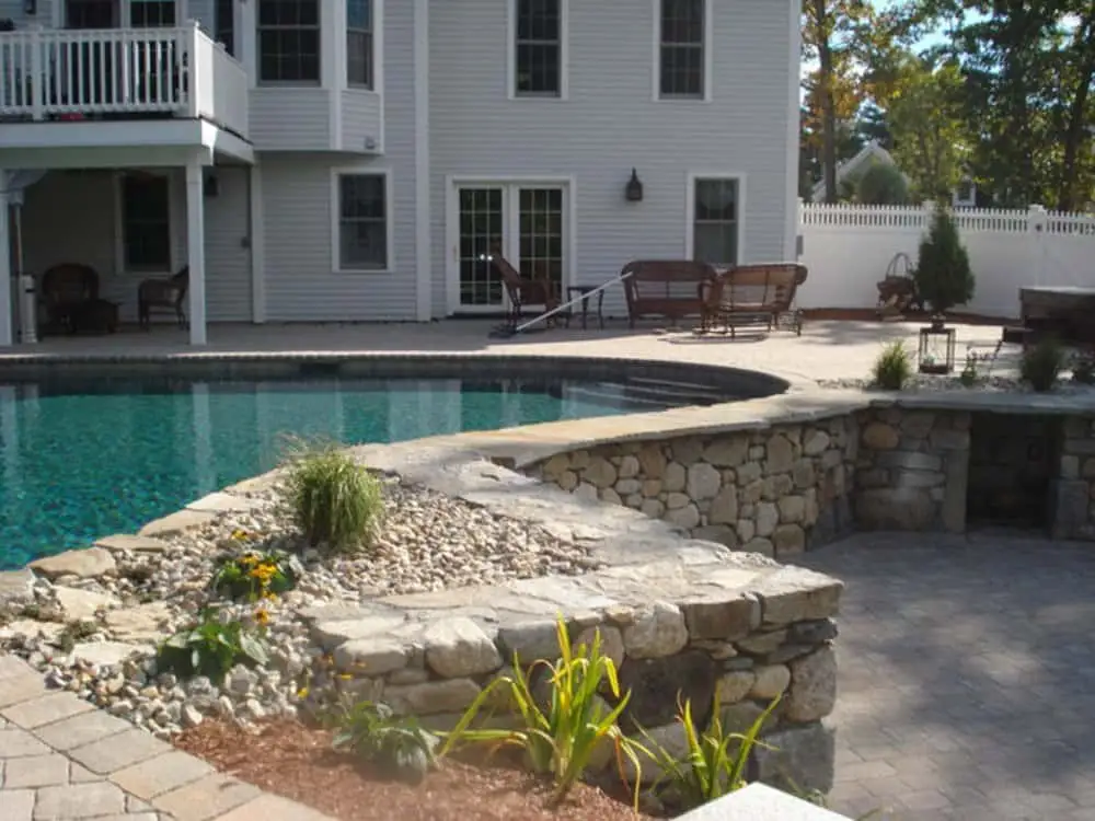 Modern semi-inground pool with custom stone coping and surrounding patio Modern semi-inground pool with custom stone coping and surrounding patio