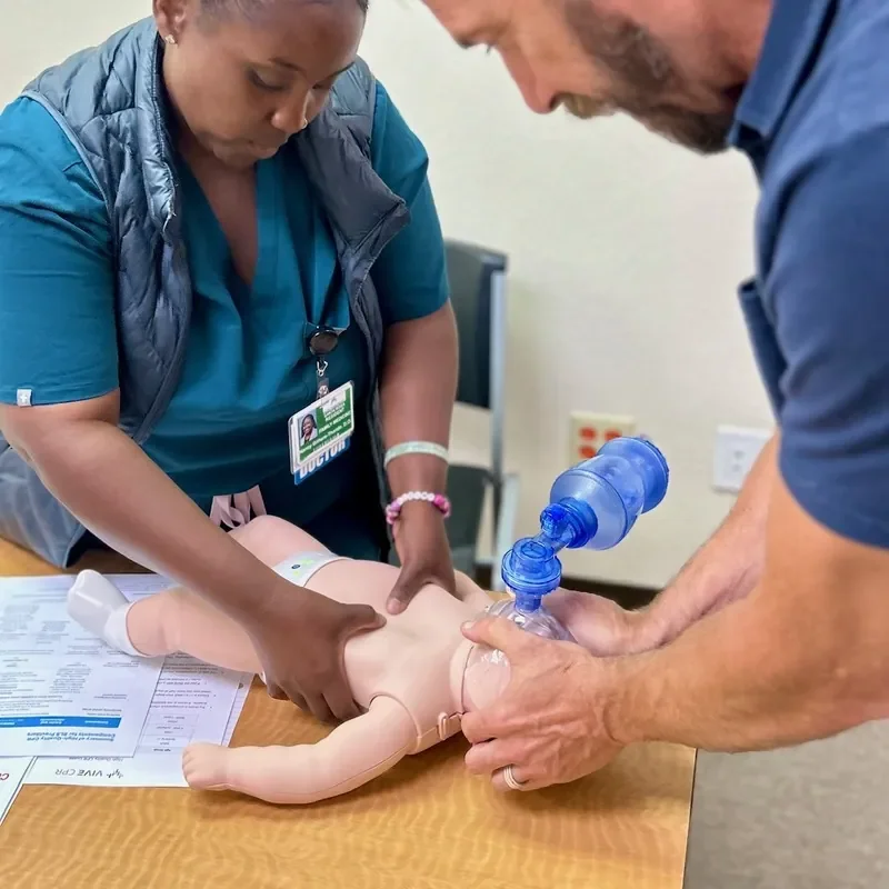 A diverse group of healthcare students practicing pediatric advanced life support on an infant manikin