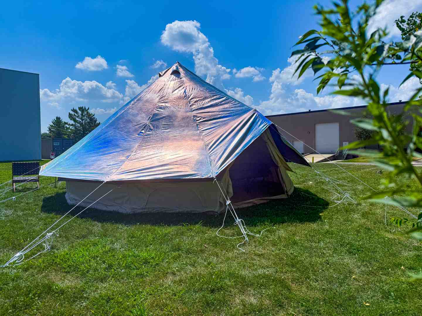 Happy campers enjoying a luxurious canvas bell tent with a silver protector cover in a sunny, natural setting - canvas tent protector