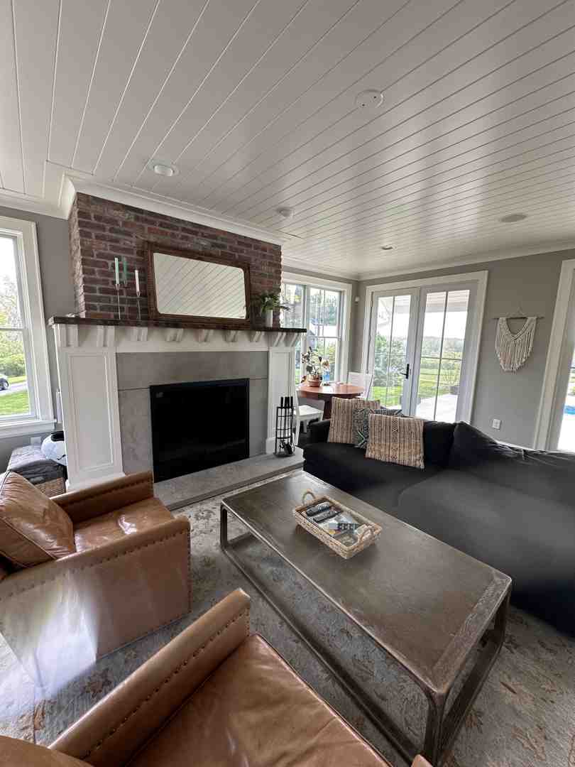 A family enjoying an open-concept living area with a central brick fireplace and large windows - Mid Century Modern Homes A family enjoying an open-concept living area with a central brick fireplace and large windows - Mid Century Modern Homes