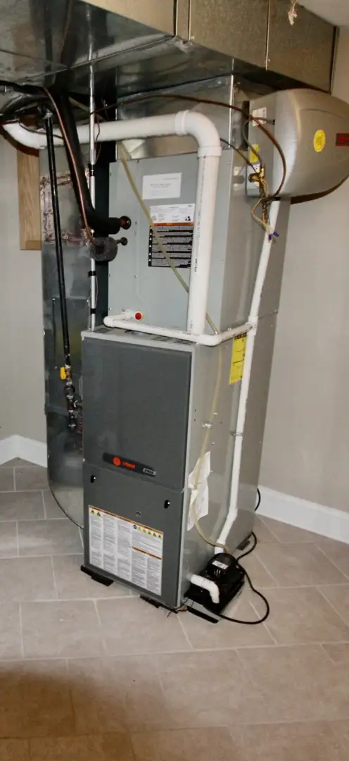 Technician inspecting the indoor unit of a geothermal system in a clean mechanical room - geothermal heat pump install