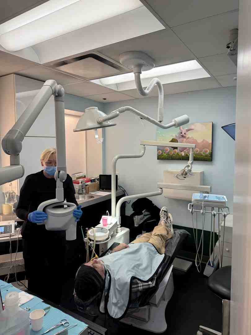 A patient sitting in a dental chair, gently guided by a dental professional, undergoing a 3D CBCT scan of their head and neck - airway dentist for adults