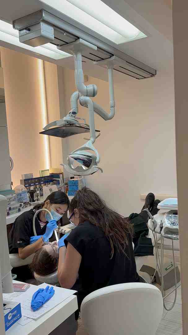 friendly dental hygienist cleaning a patient's teeth - Cavity Prevention NYC