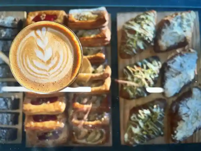 A barista expertly pouring latte art into a pristine white cup, showcasing the skill and dedication behind each coffee at Flinders Lane Cafe. - Sunshine Coast breakfast