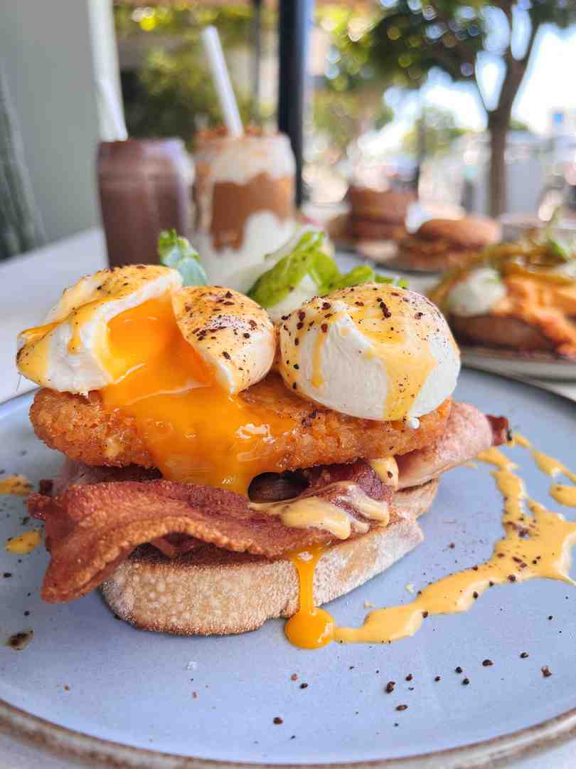 of the Bacon Benny, focusing on the poached eggs and hollandaise sauce - Flinders Lane's Top 5 Brekky Favourites You’ll Come Back For