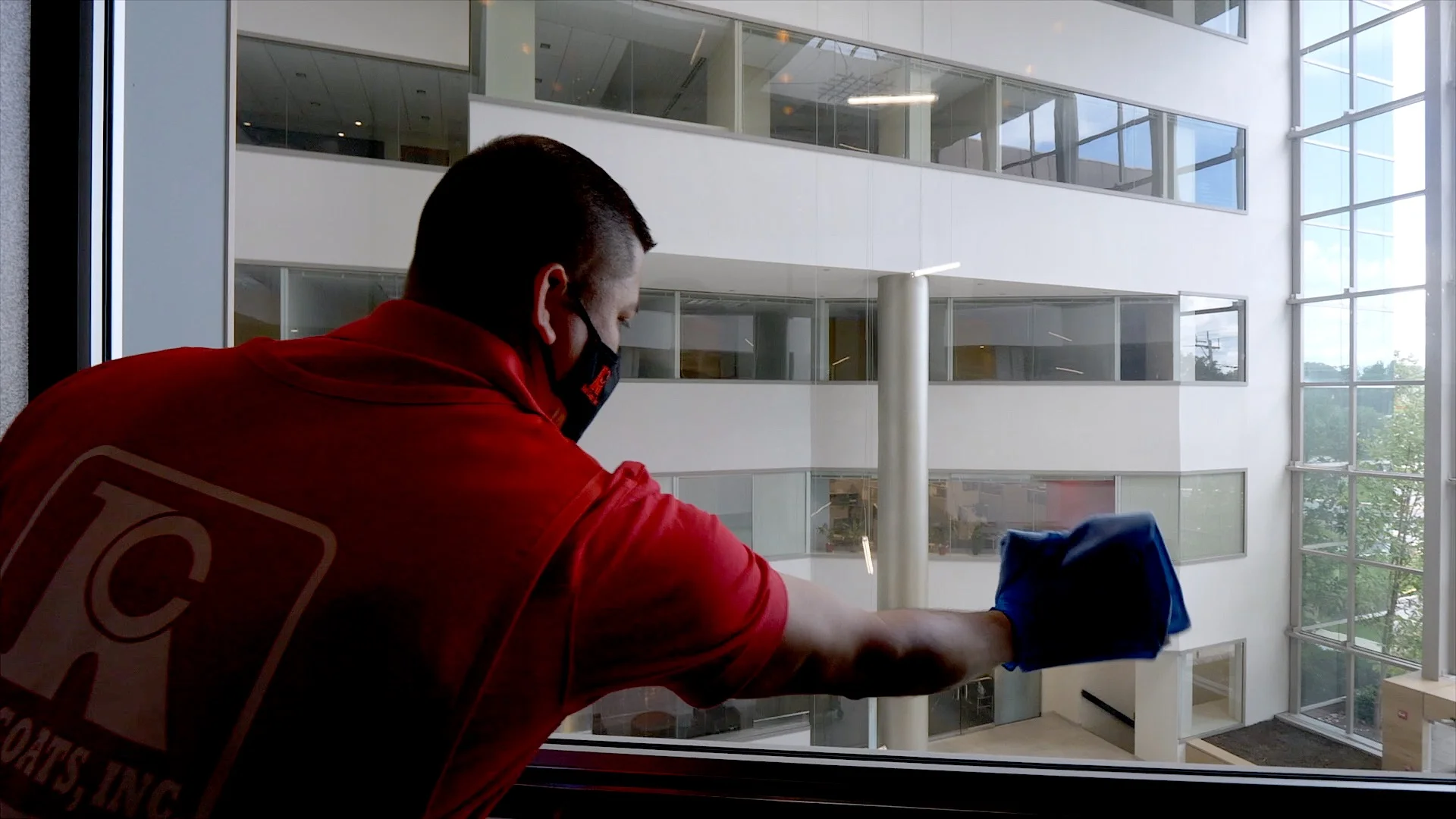 Commercial cleaning technician in Red Coats uniform standing at a clean facility entrance
