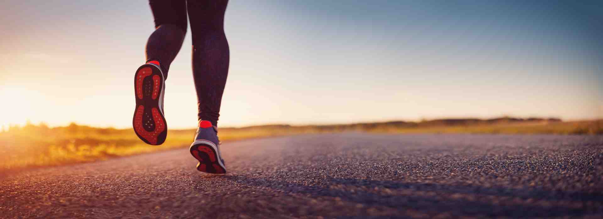 A runner's feet hitting the pavement in cushioned running shoes - plantar fasciitis shoes