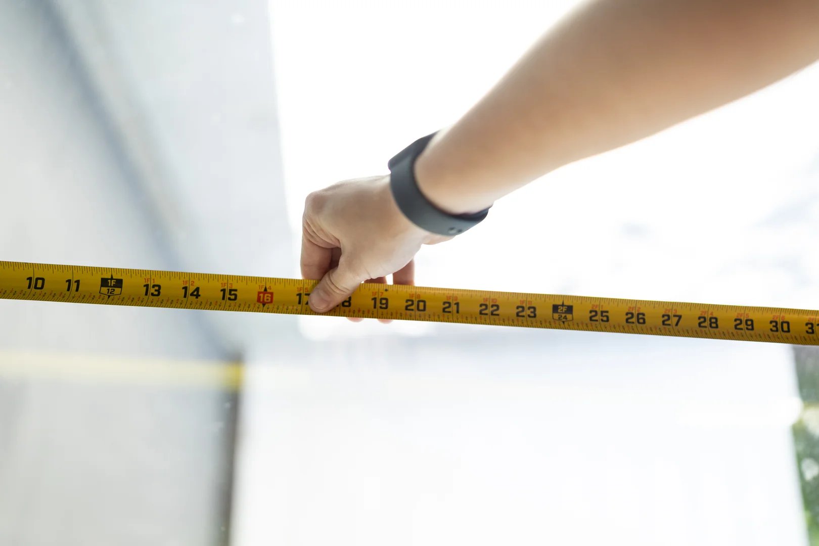 A professional contractor measuring a fascia board with a tape measure to plan bracket placement A professional contractor measuring a fascia board with a tape measure to plan bracket placement