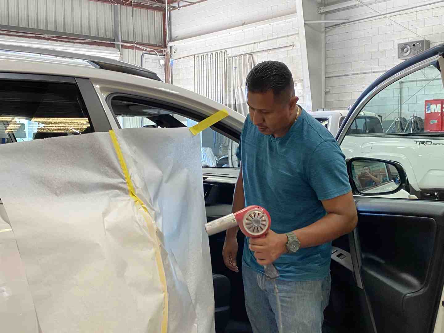 person using fabric steamer on car window - auto window tint removal