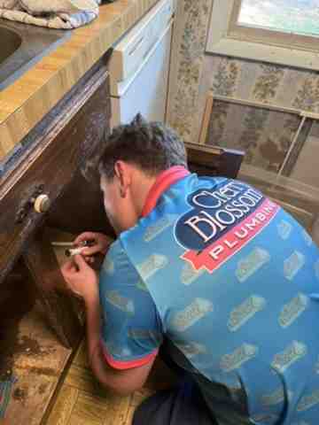 professional plumber installing a garbage disposal under a sink - garbage disposal installation alexandria