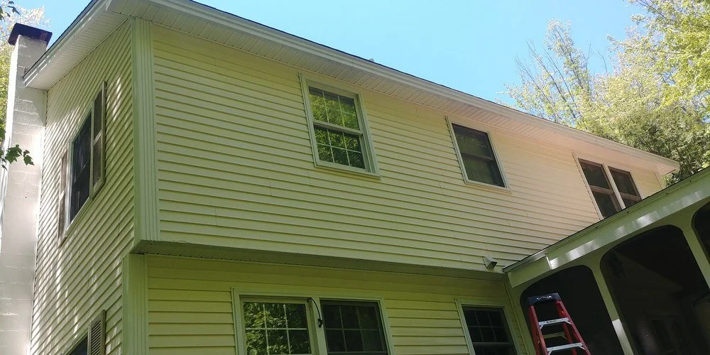 Technician applying eco-friendly restoration coating to a residential property in Amherst - eco vinyl siding restoration