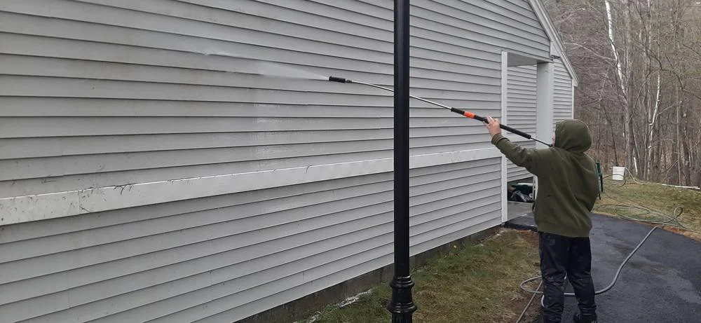 Technician using professional-grade power washing equipment on a residential driveway - best power washing company Technician using professional-grade power washing equipment on a residential driveway - best power washing company