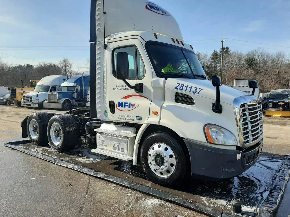 Professional technician using high-pressure equipment to clean a semi-truck - truck fleet cleaning