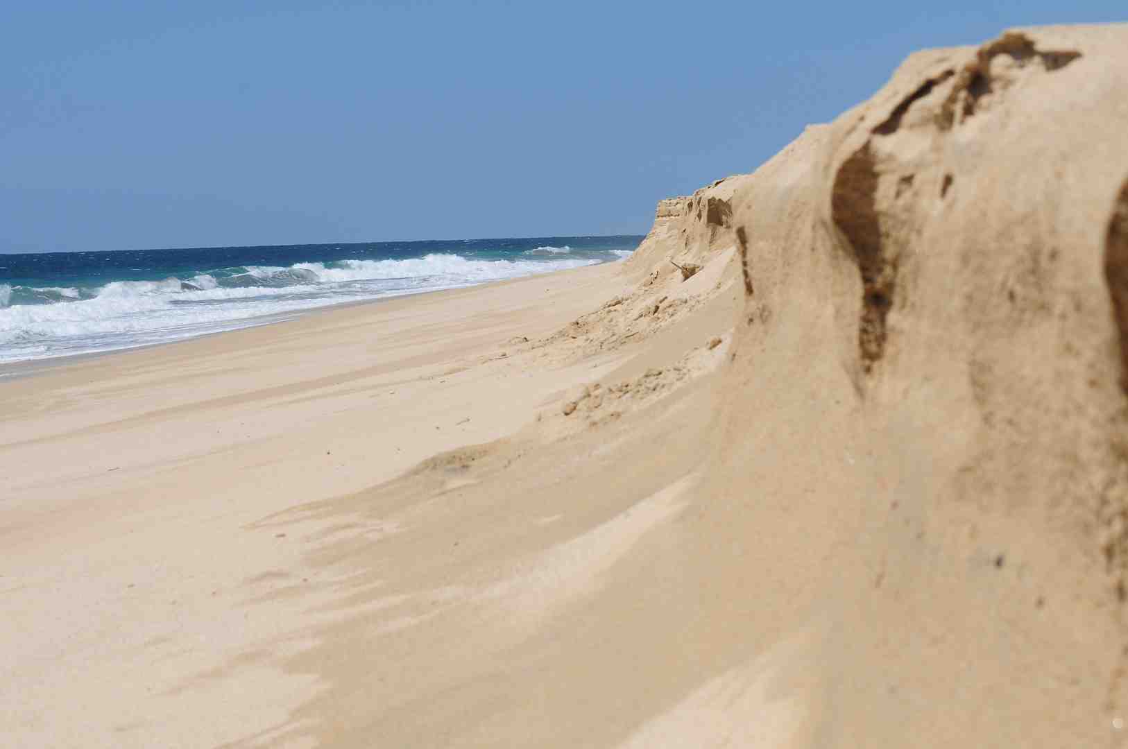 A vibrant image of kitesurfers riding the waves on the Sea of Cortez, with the arid mountains of Baja California Sur forming a dramatic backdrop under a clear blue sky - Cabo airport to Los Barriles
