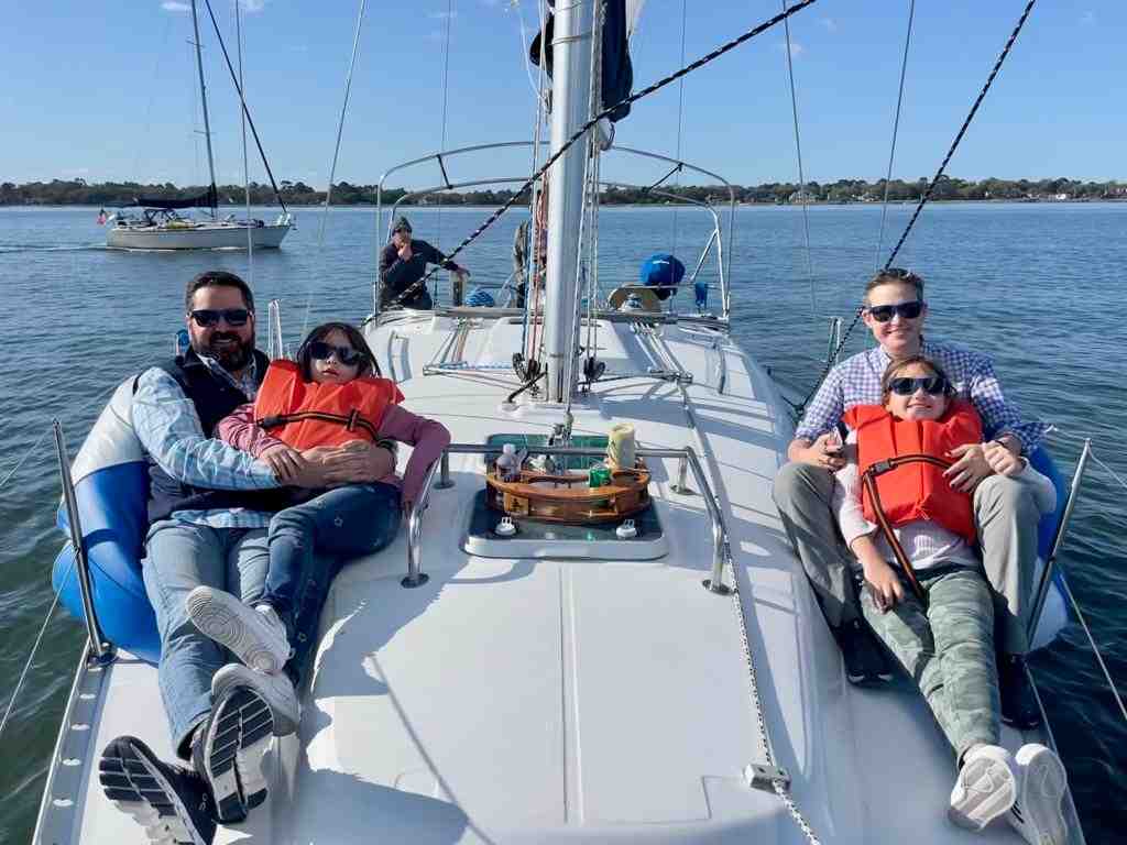A family confidently steering a sailboat on open water - bareboat charter vs time charter