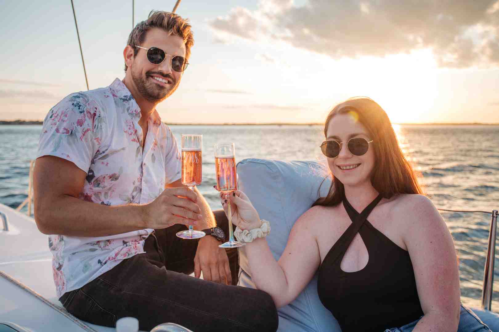 Couple dressed in resort casual attire enjoying a drink on a boat at sunset - Charleston evening cruise