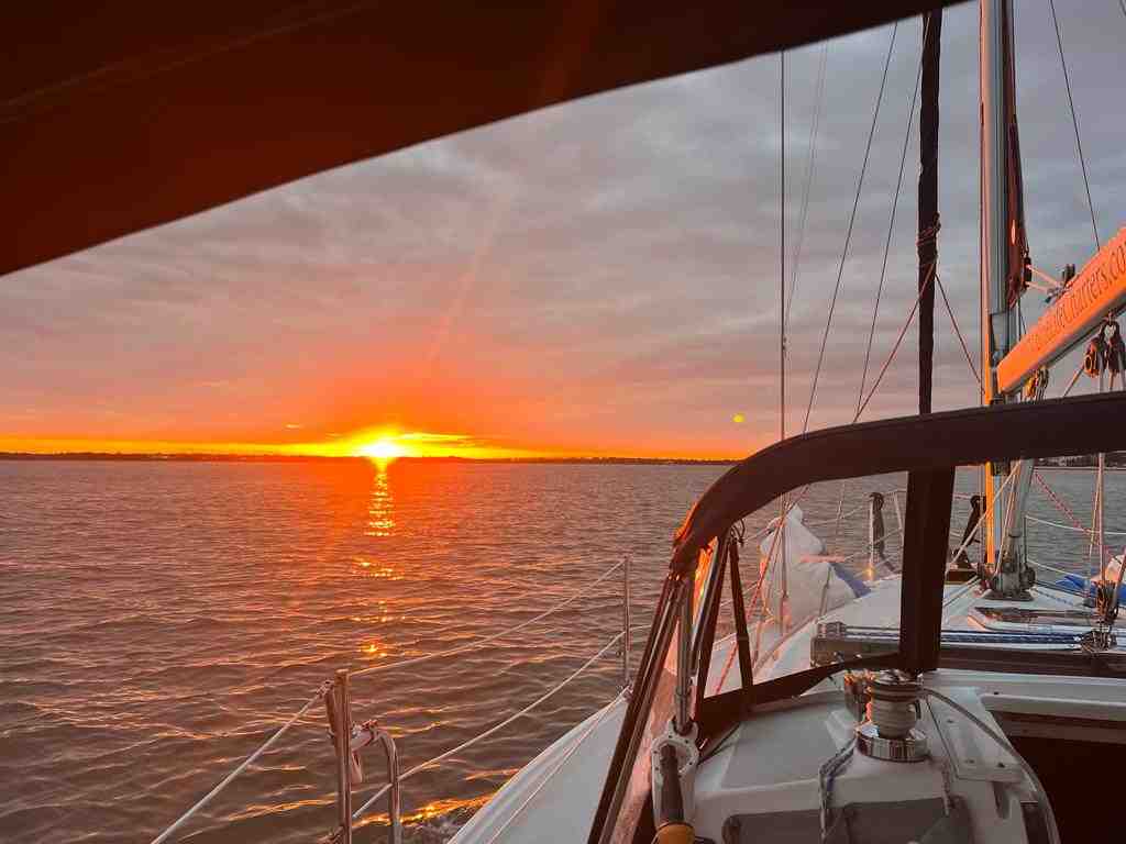 Luxury sailing yacht navigating Charleston Harbor at sunset - luxury yacht rentals in charleston sc