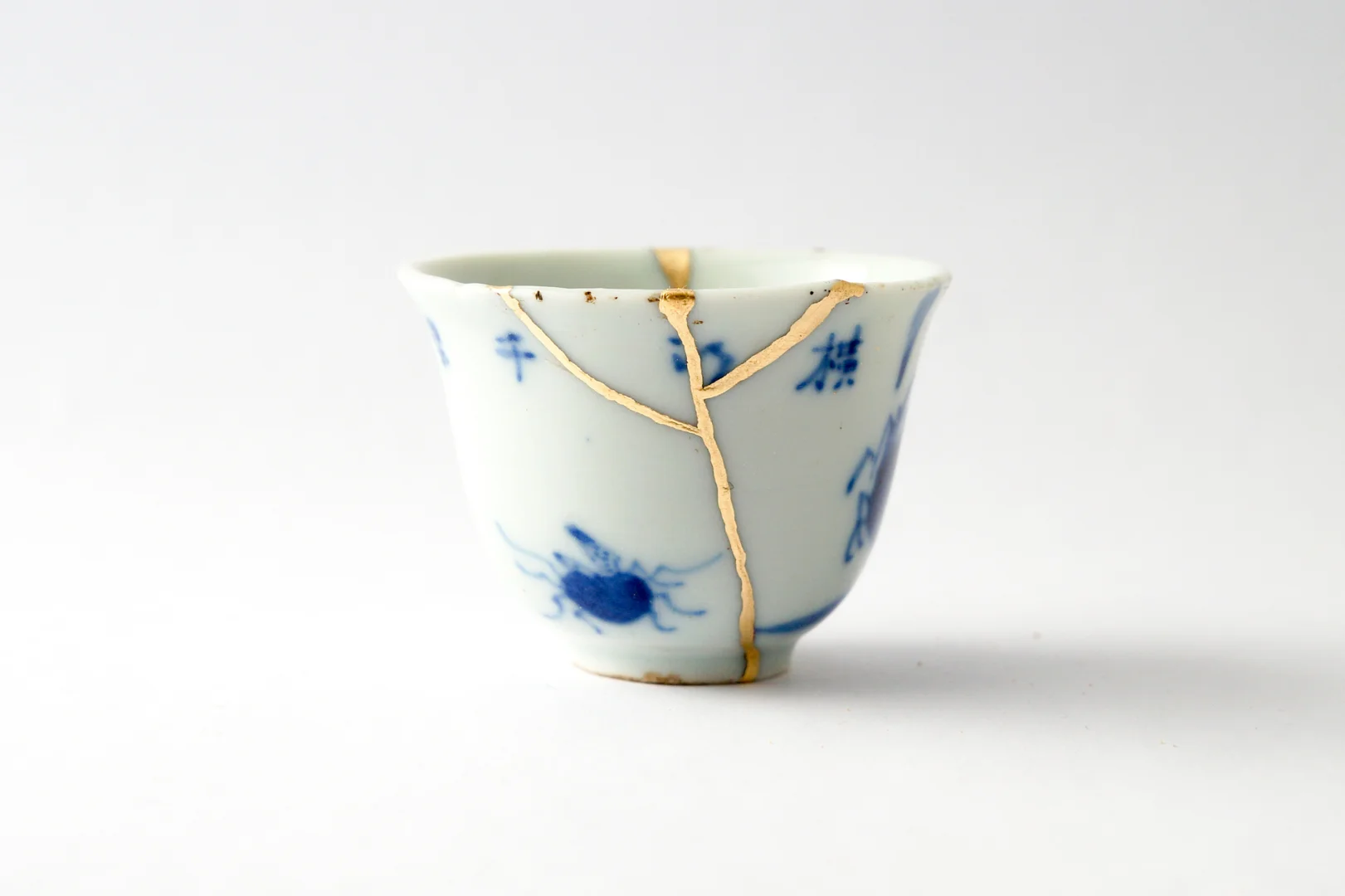 cracked ceramic vessel repaired with gold lacquer in muted yellow tones