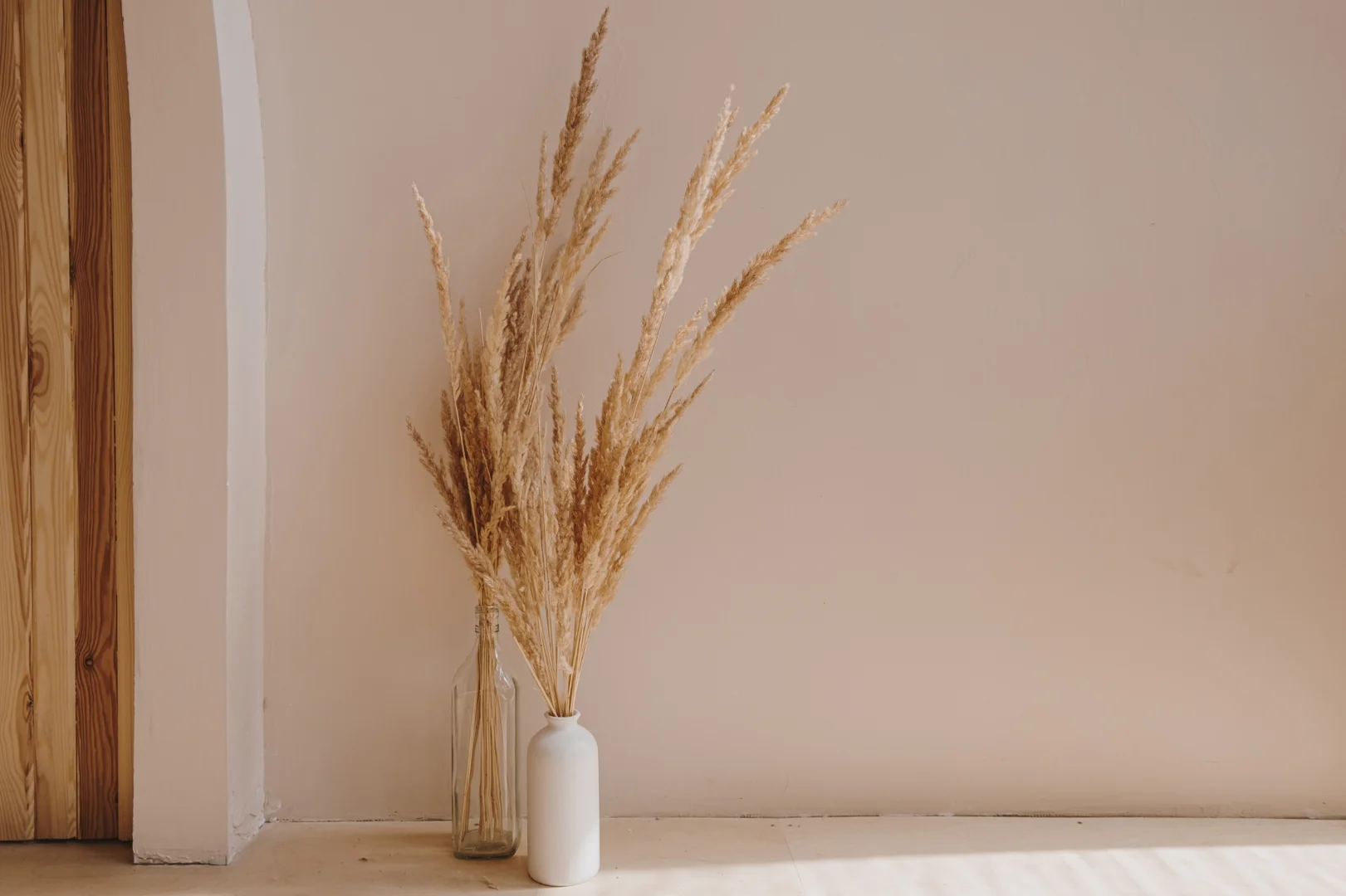 amber glass vase with dried grass against a muted yellow background