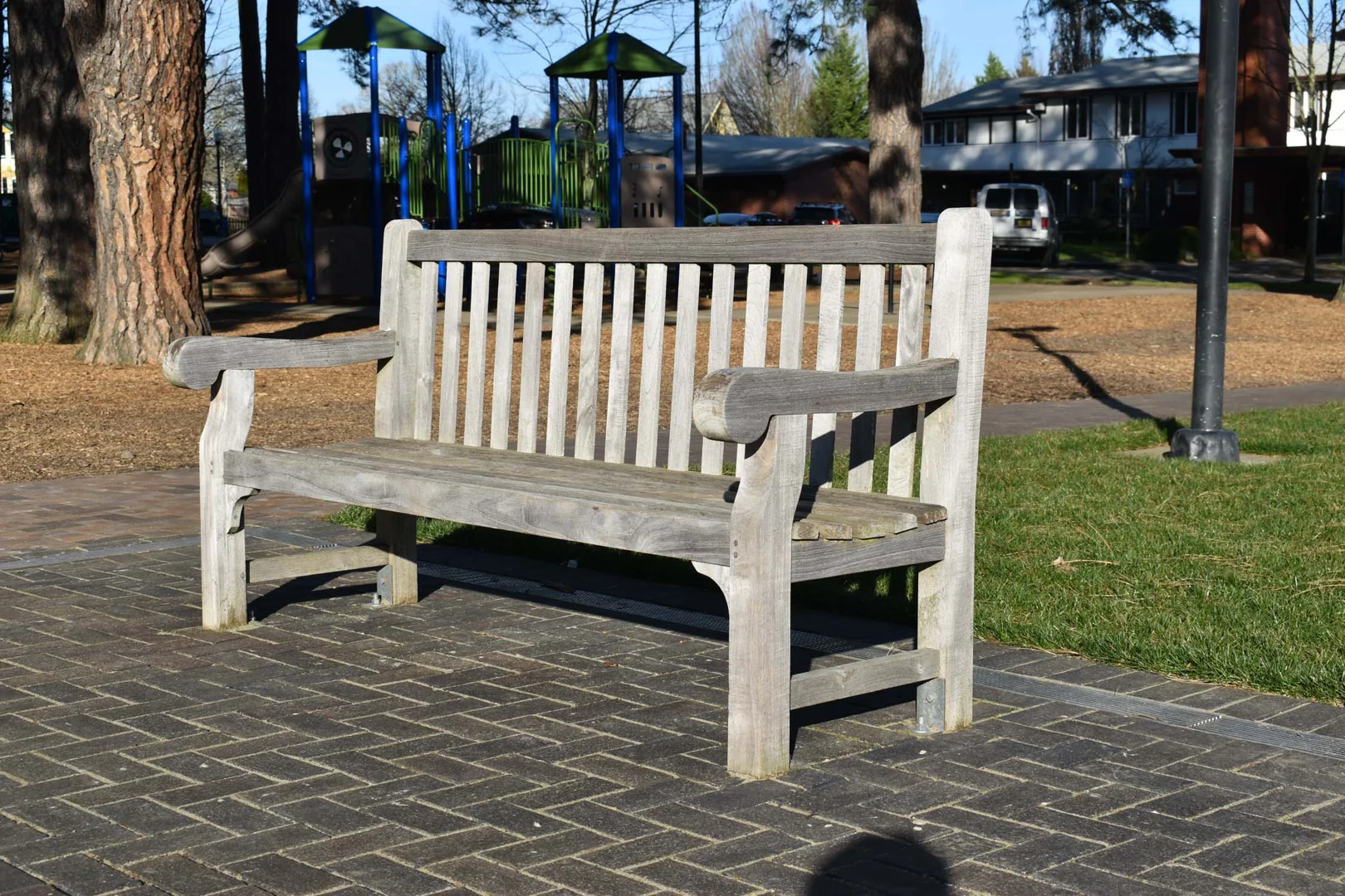 Naturally weathered silver patina teak bench on a stone terrace
