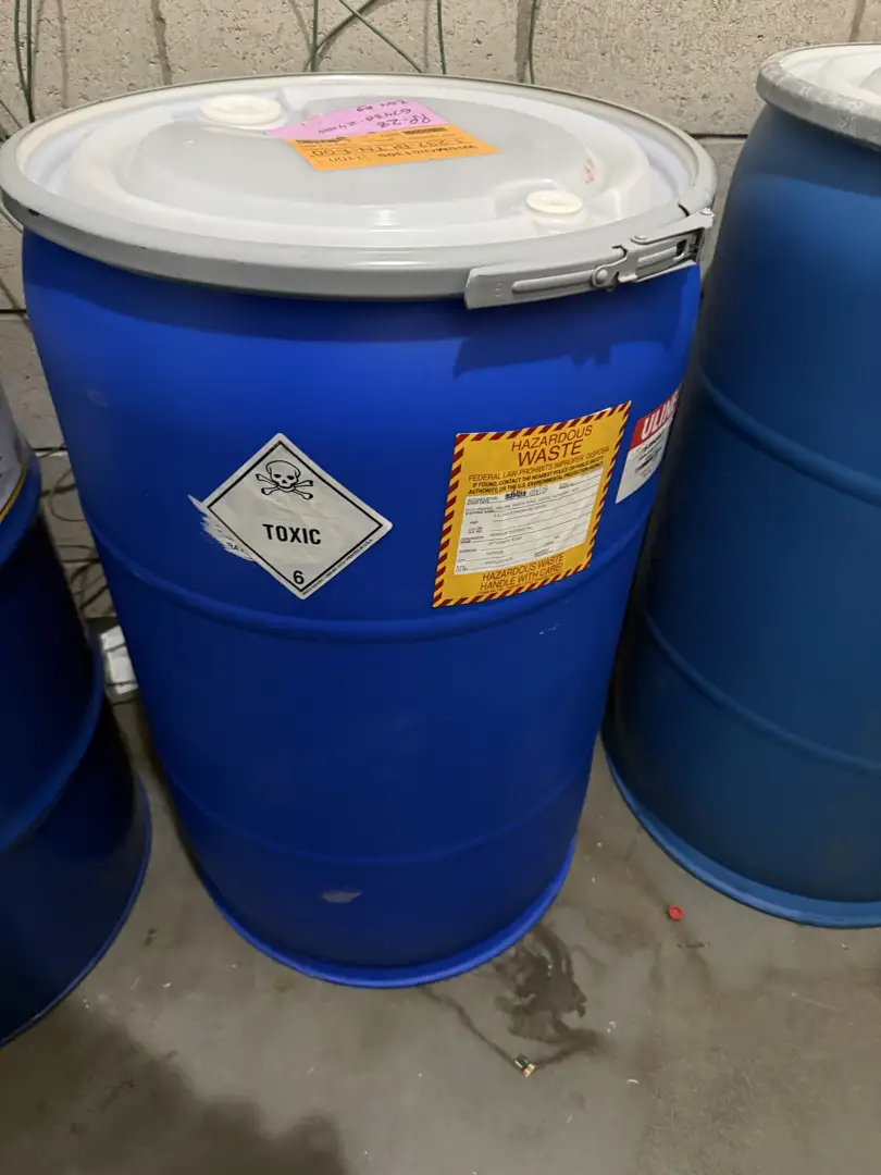Hazardous waste warning labels on industrial drums in a storage facility - environmental waste management Hazardous waste warning labels on industrial drums in a storage facility - environmental waste management