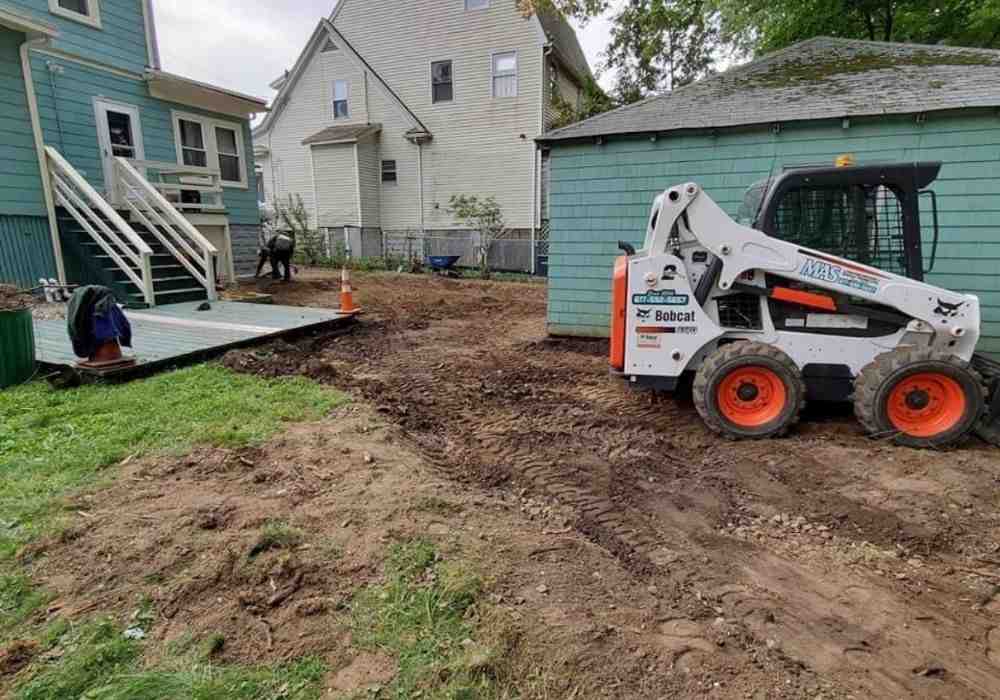 A sloped backyard showing excavation work being done for a new wall installation - concrete wall fence cost