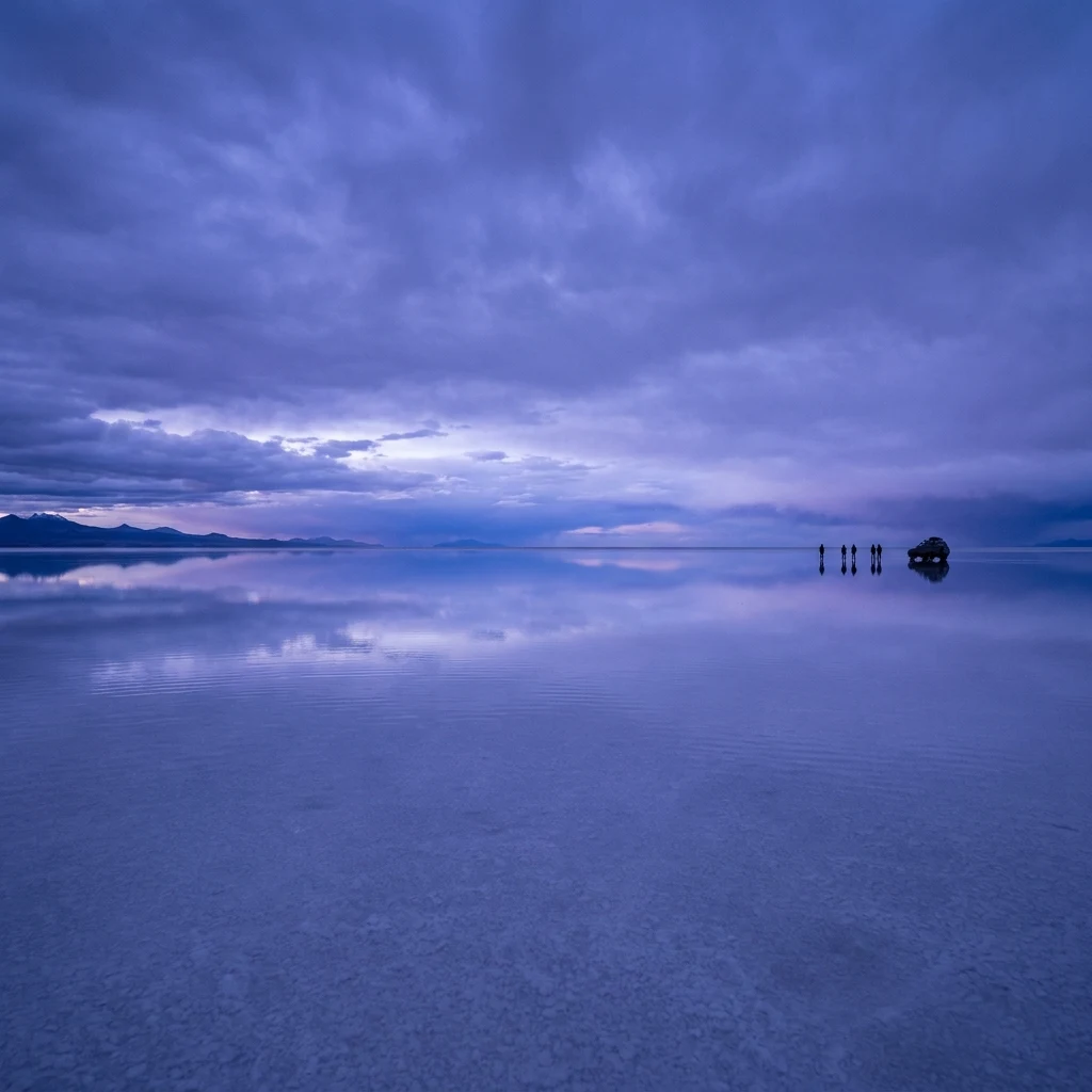 A vast salt flat in the Salar de Uyuni reflecting a violet blue hour sky after a light…