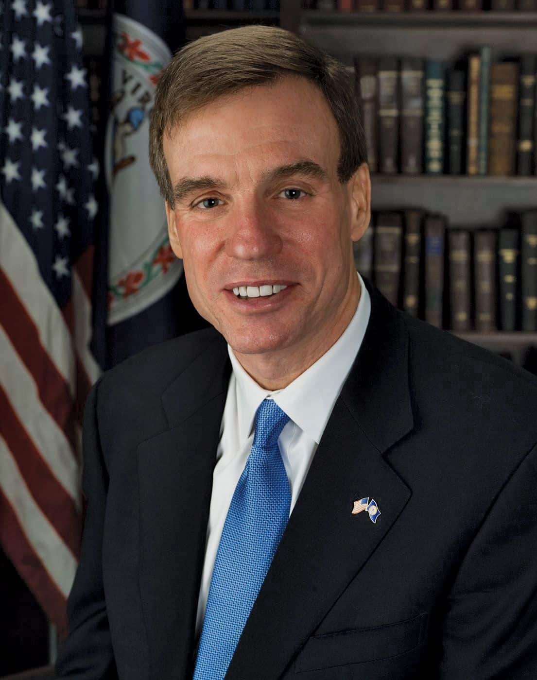 Mark Warner en entorno profesional con bandera estadounidense