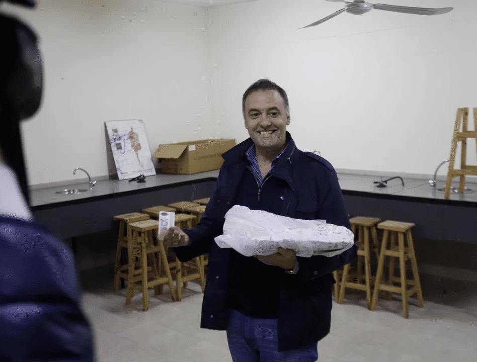 Manuel Adorni sosteniendo documento en centro de votación