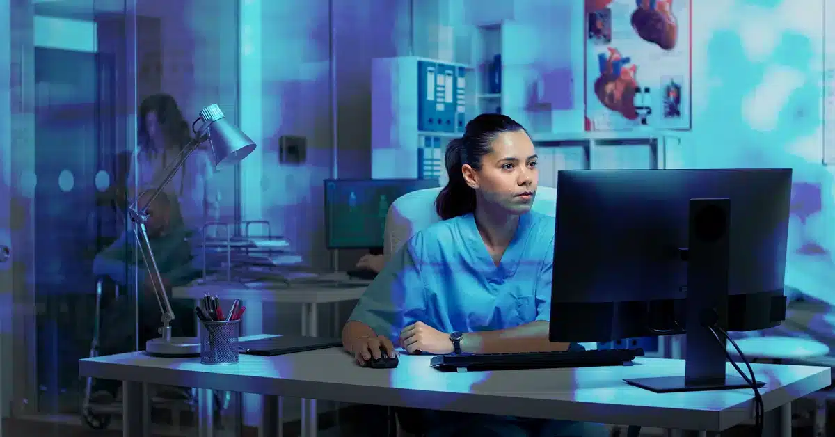 Profesional médica trabajando en computadora en entorno hospitalario