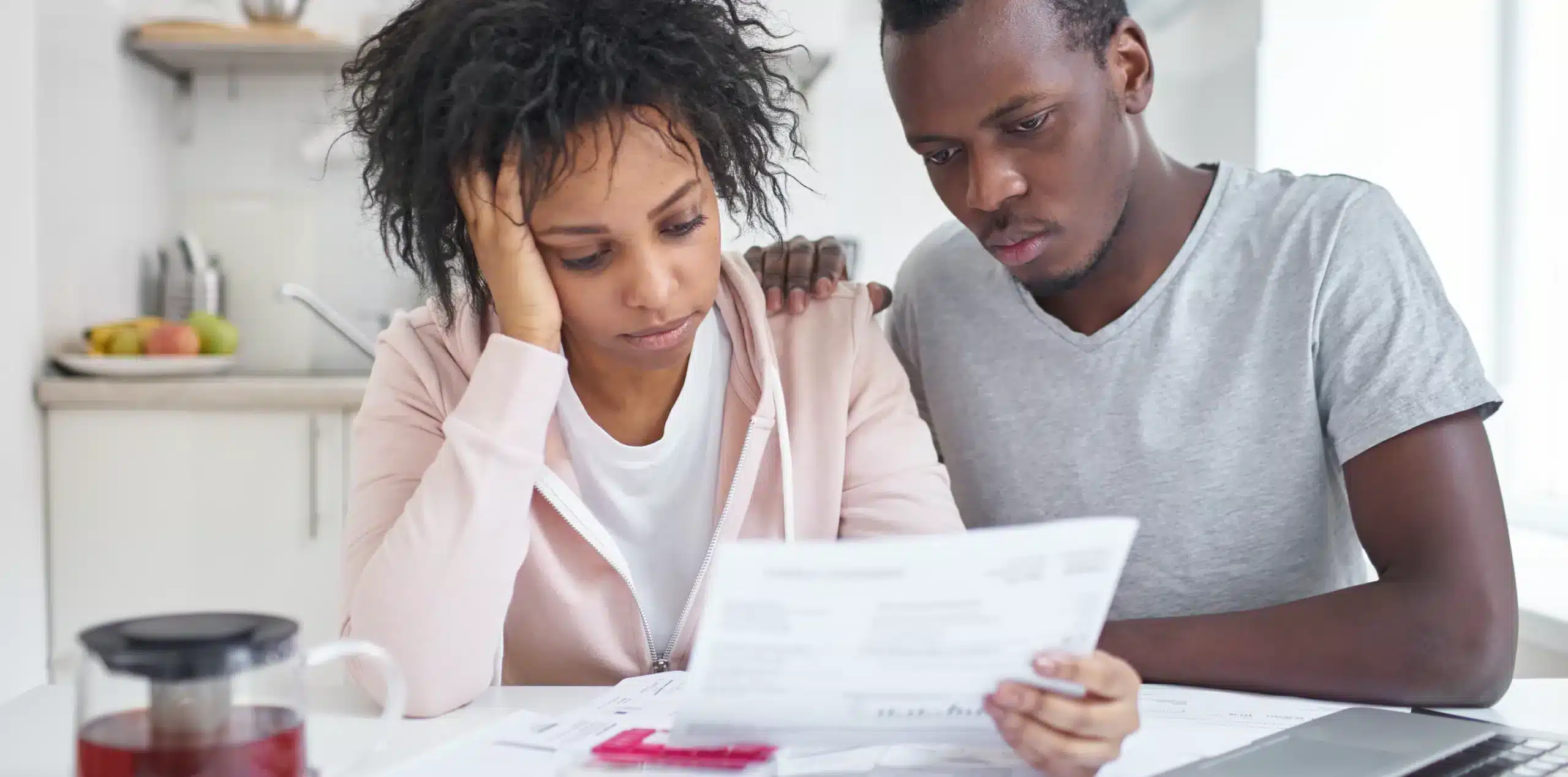 Pareja revisando documentos de vivienda con expresi&oacute;n preocupada