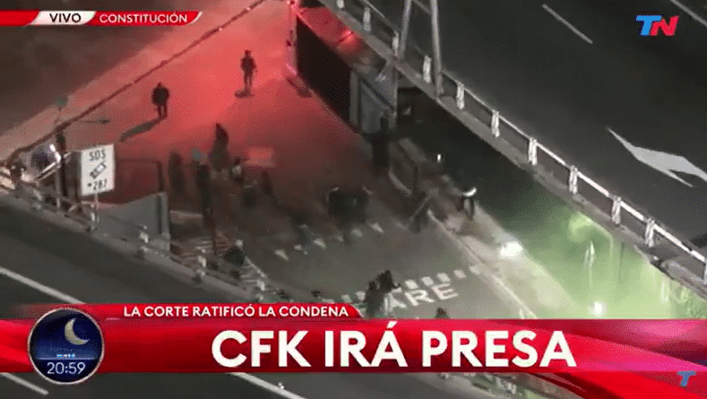 Manifestantes kirchneristas congregados frente al edificio de TN con luces rojas y verdes de fondo