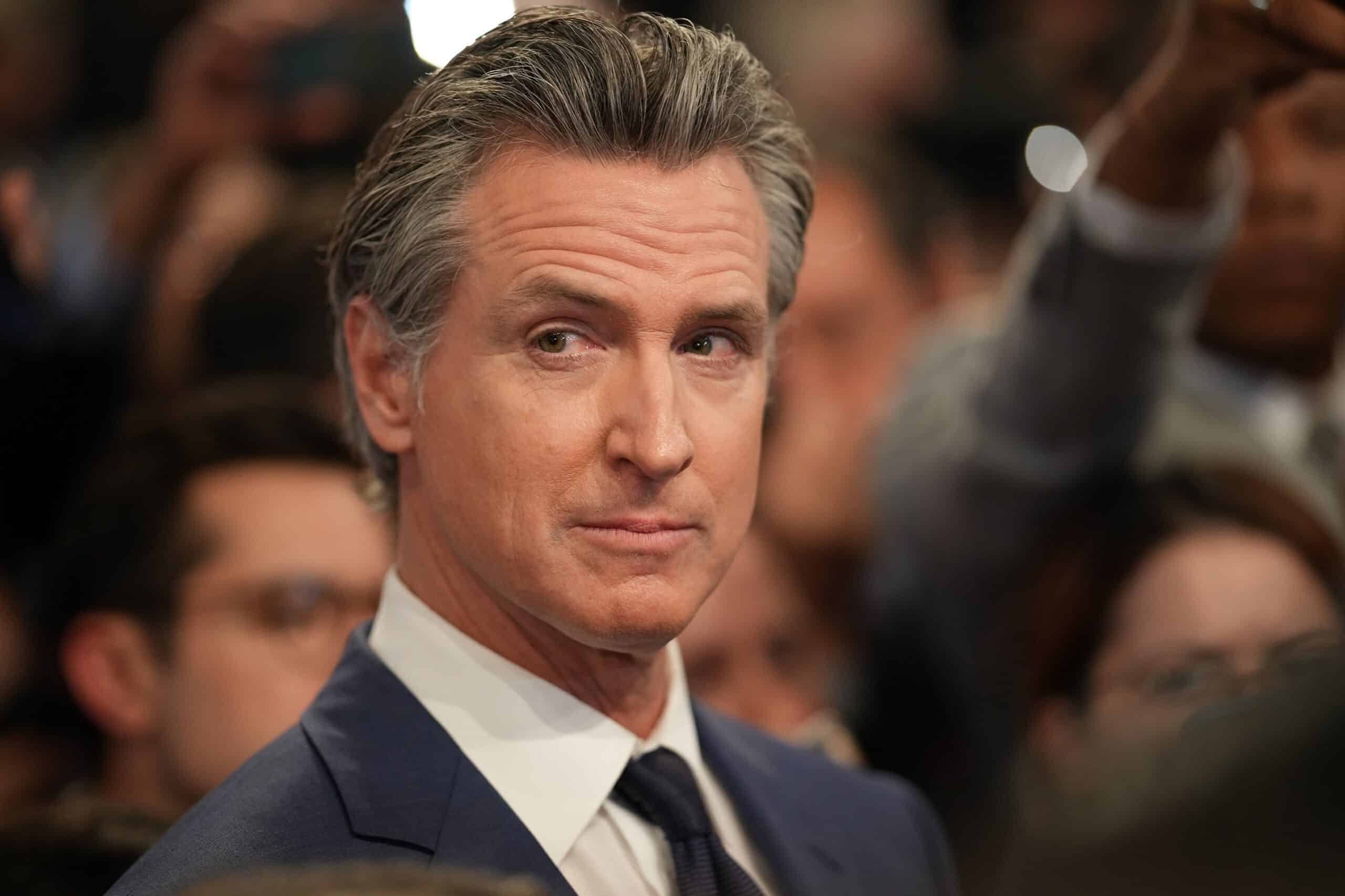 Gavin Newsom en ambiente tenso rodeado de personas