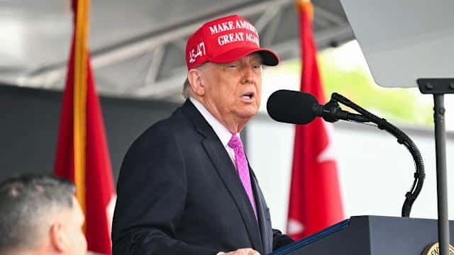 Trump discursando con banderas de fondo