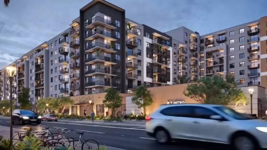 Moderno edificio residencial con balcones y áreas verdes cerca de estación de tren