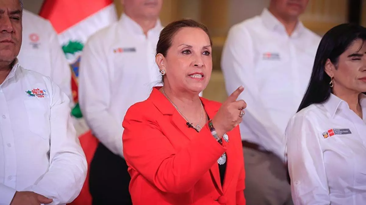 Dina Boluarte dando discurso con bandera peruana de fondo