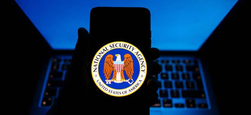 Tel&eacute;fono mostrando logo de la NSA con teclado de computadora de fondo