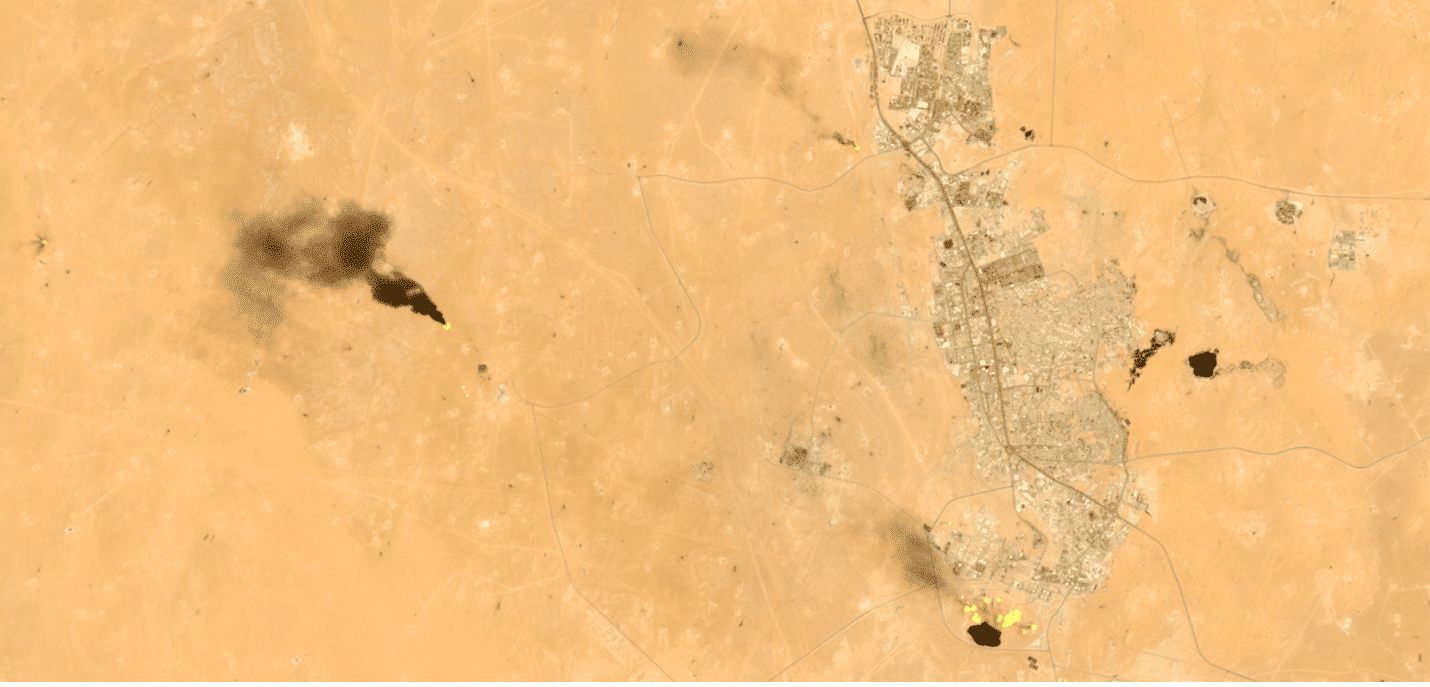 Columnas de humo negro en paisaje des&eacute;rtico cerca de zona urbana